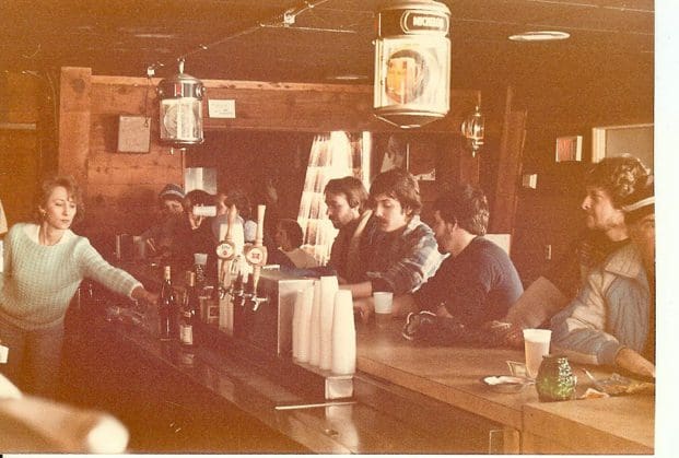 Vintage photo of people sitting at a bar counter in a cozy pub.