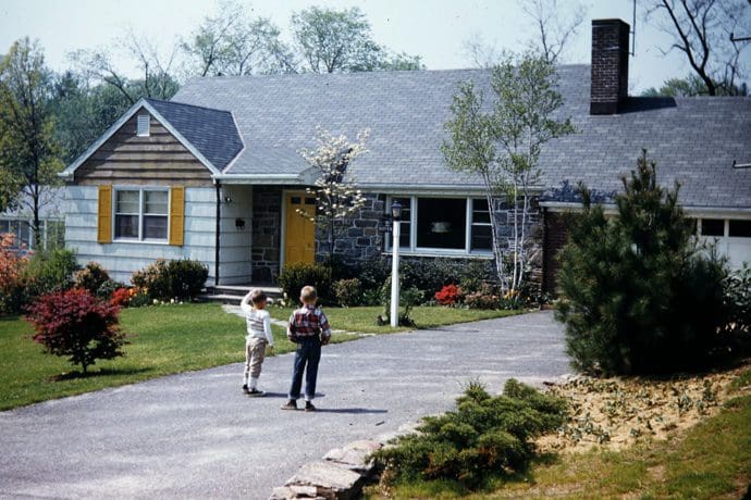 Two children outside a suburban house.