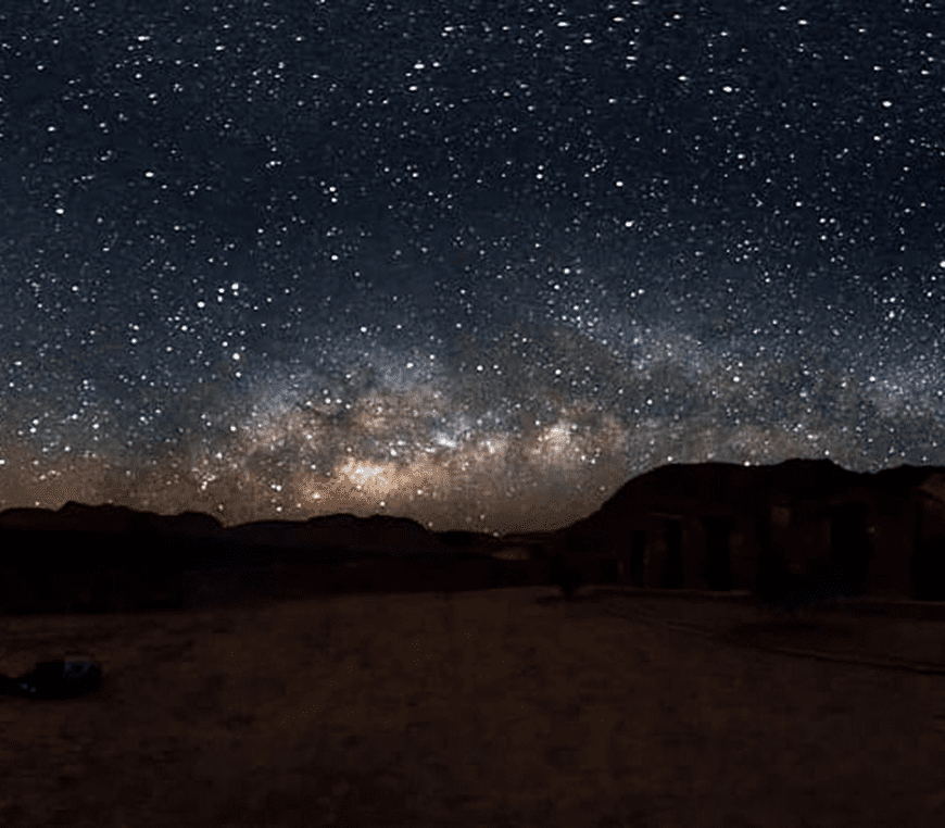 Starry night sky over distant mountains.