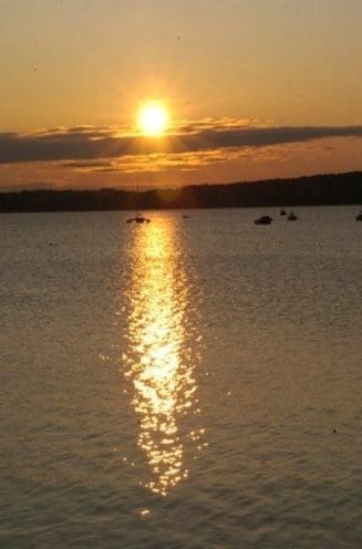 Sunset over calm lake with reflection.