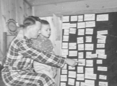 Two young men examining a wall covered with numerous notes or cards.