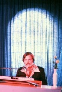 Man playing piano on stage with microphone.