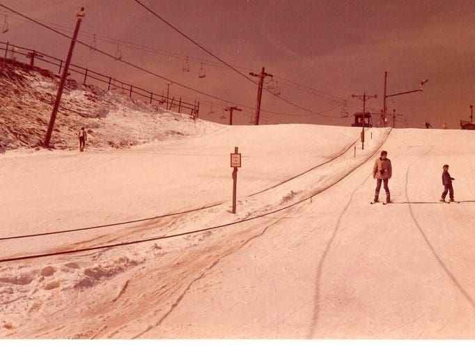 Skiers on snowy slope with ski lift.