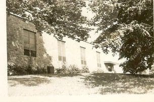 Old building surrounded by trees and grass.