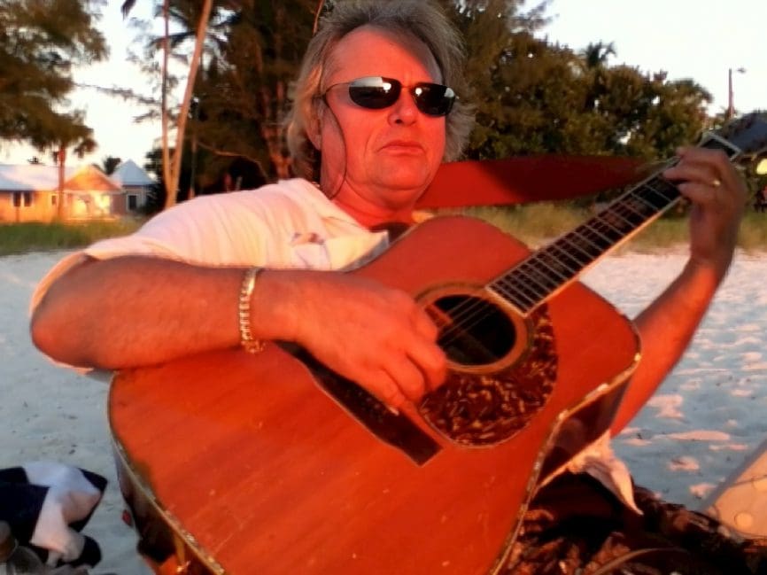 Man playing guitar on the beach.