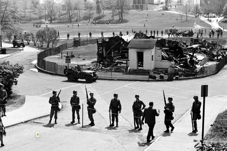 Soldiers guarding area with burnt building remains.