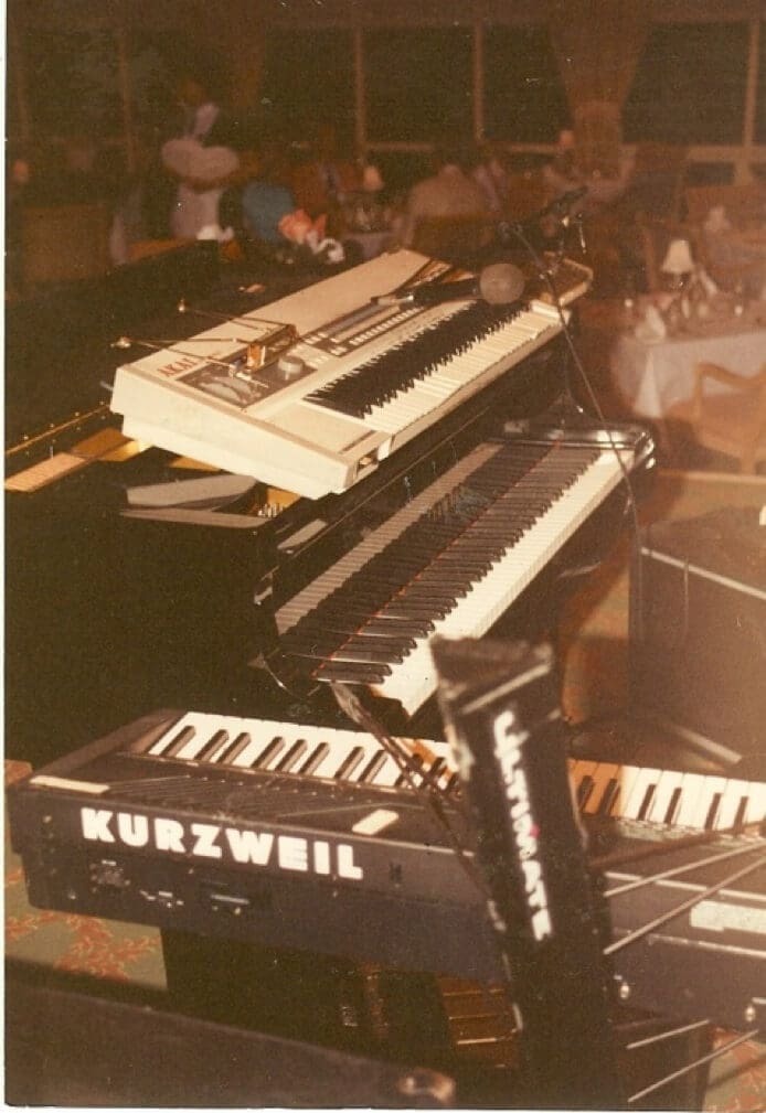 Three keyboards stacked on stands at a music setup.