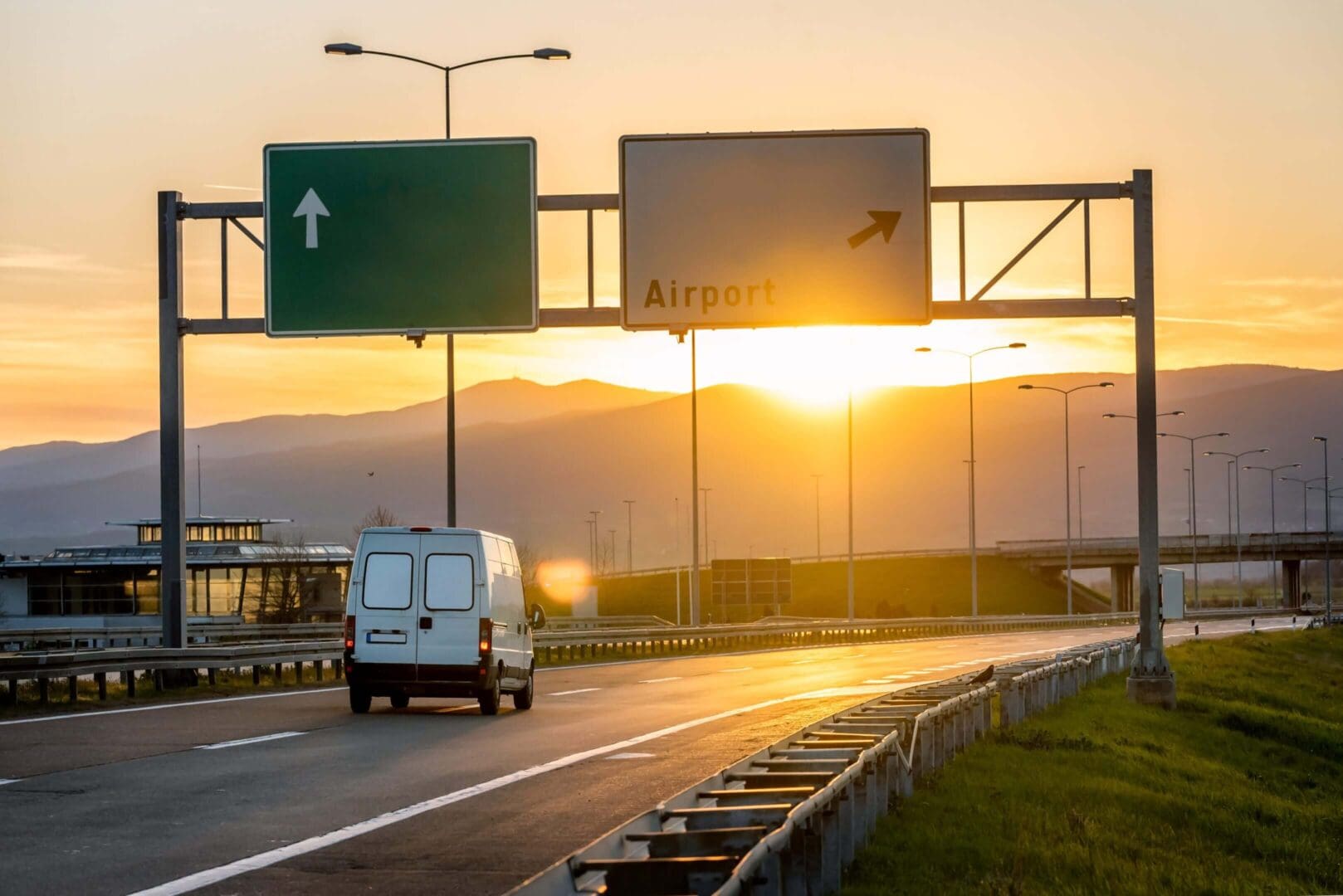Van driving towards airport at sunset.