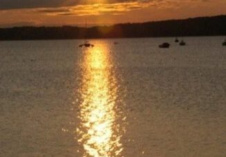 Sunset over calm lake with reflection.