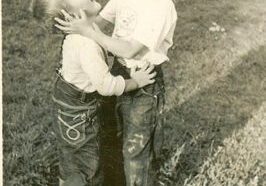 Two young boys playing and hugging outside.
