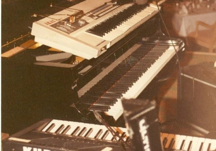 Three keyboards stacked on stands at a music setup.