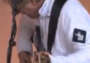 Musician playing guitar in white jacket.