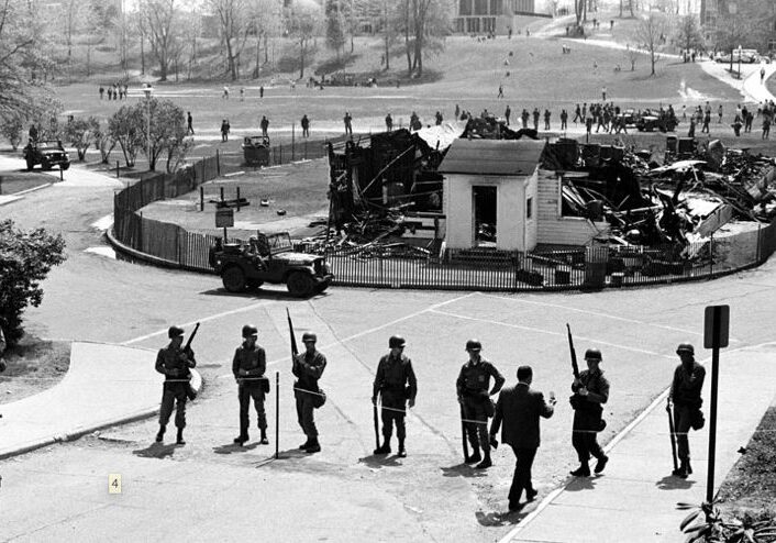 Soldiers guarding area with burnt building remains.