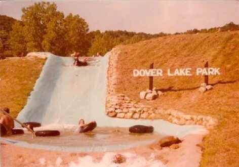 People enjoying water slide at park.